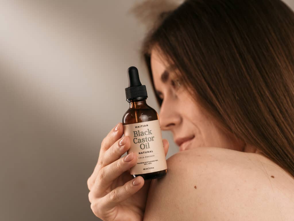 a woman holding a bottle of pure castor oil